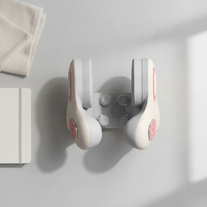 White handheld massager on a light gray surface with a white towel and notebook in the background.